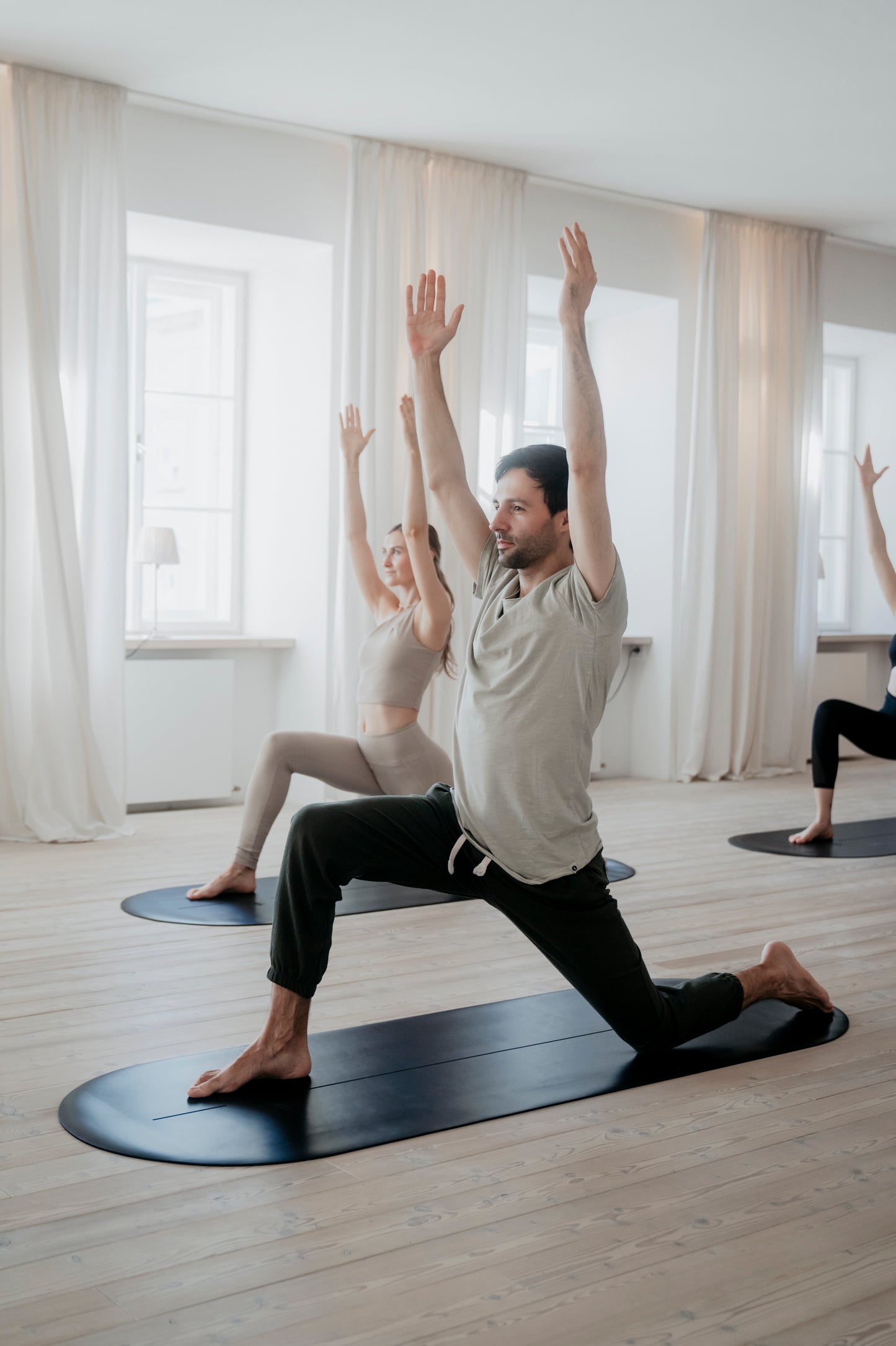 Gruppe beim Yoga mit Lunge-Position auf der ALL BLACK Yogamatte, ideal für dynamische Übungen.