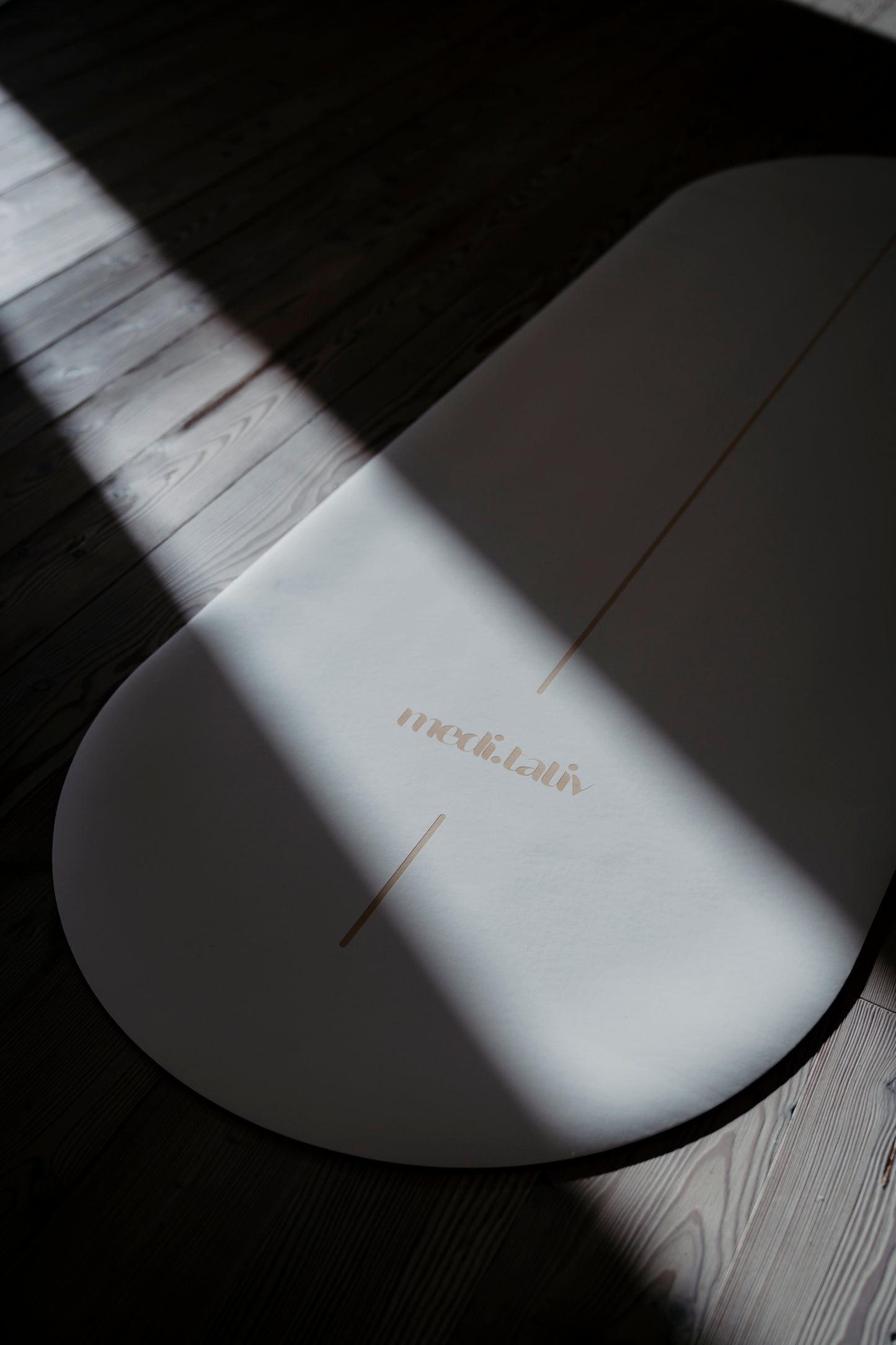 Detailansicht der GOLDEN SAND Yogamatte im Licht und Schatten, mit sanften goldenen Details auf einem edlen weißen Untergrund.