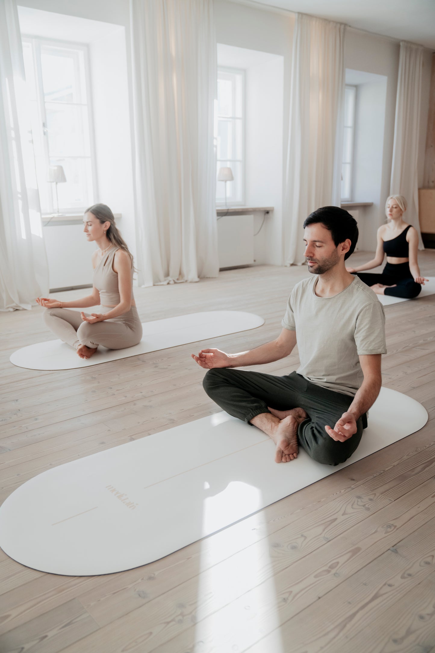 Eine Yoga-Gruppe in einem hellen, ruhigen Studio, meditierend auf der GOLDEN SAND Yogamatte mit elegantem Design und extremer Rutschfestigkeit.