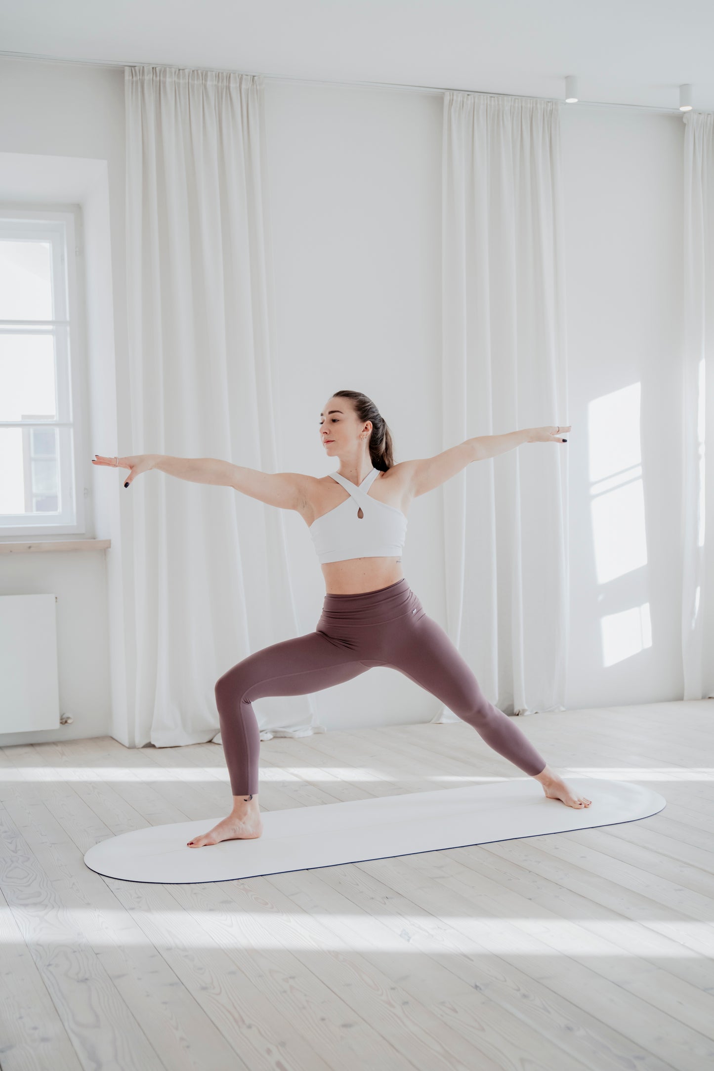 Frau praktiziert die Kriegerpose auf der GOLDEN SAND Yogamatte, perfekt für Yoga und Pilates in einem stilvollen Studio.